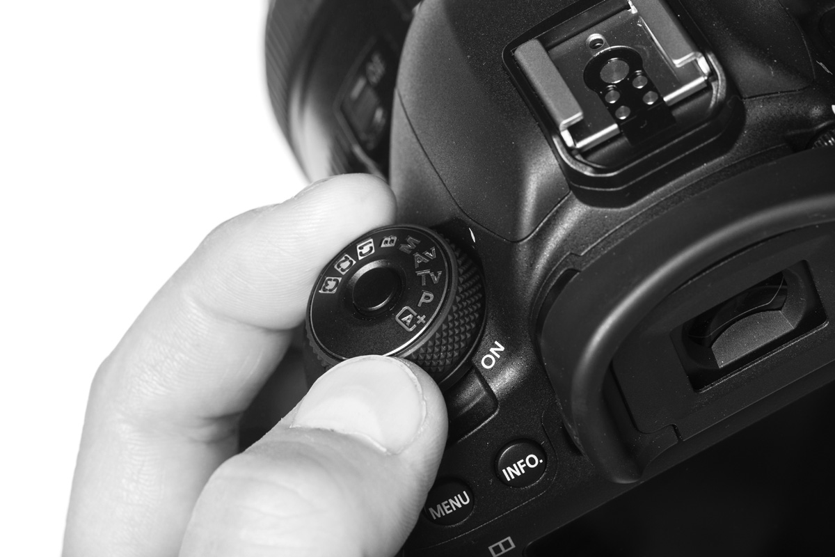 Fotocamera met hand en sceneknop in beeld