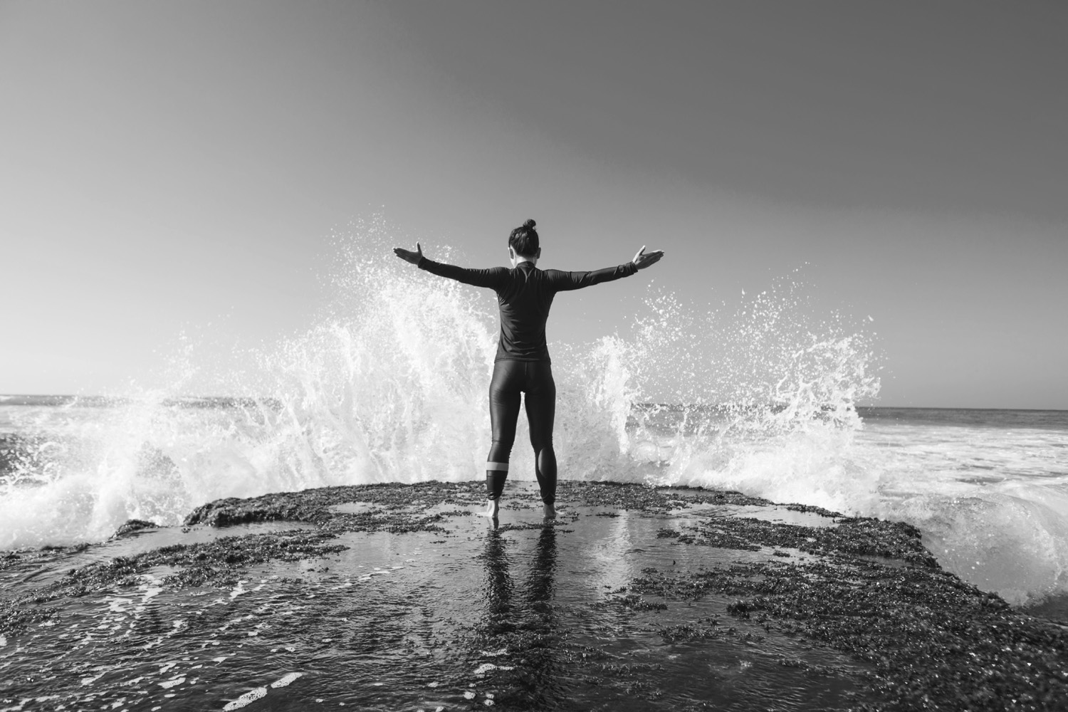 Hoe fotografeer je golven op een indrukwekkende manier? Met context zoals in dit geval met een vrouw in de voorgrond en opspattende golven.